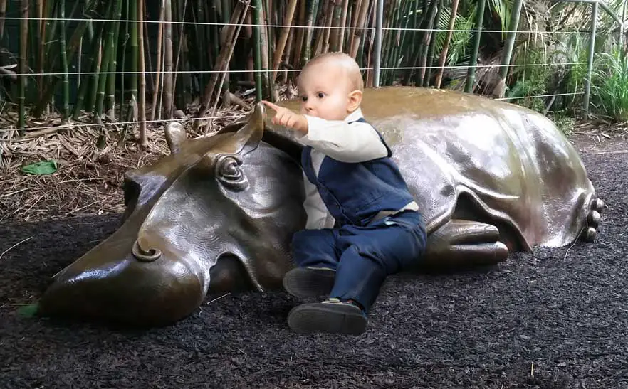 Toddler playing on hippo sculpture in play area at San Diego Zoo.