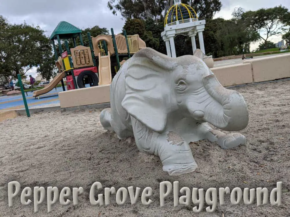 Balboa Park - Pepper Grove Playground elephant sculpture in sandbox with climbing and sliding structures in the background. 