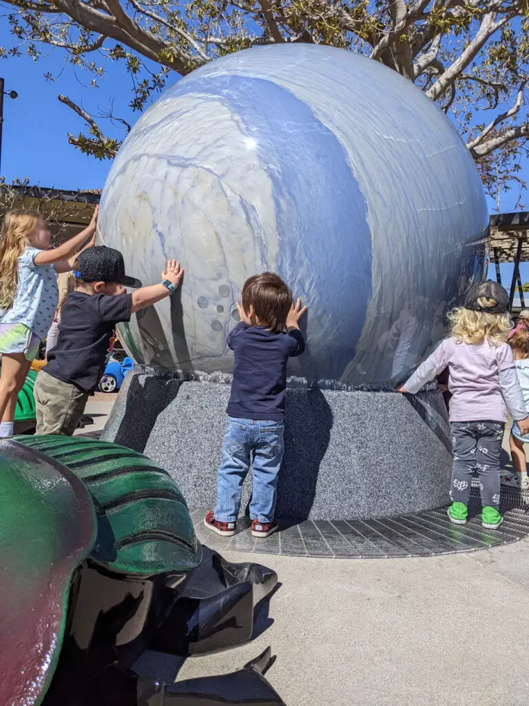 Kids spinning the stone globe at San Diego Zoo Wildlife Explorers Basecamp