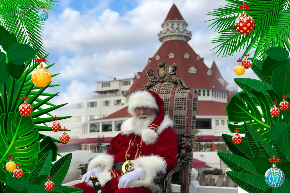 Hotel del Coronado's Santa in front of the iconic San Diego landmark surrounded by tropical foliage hung with Christmas ornaments.