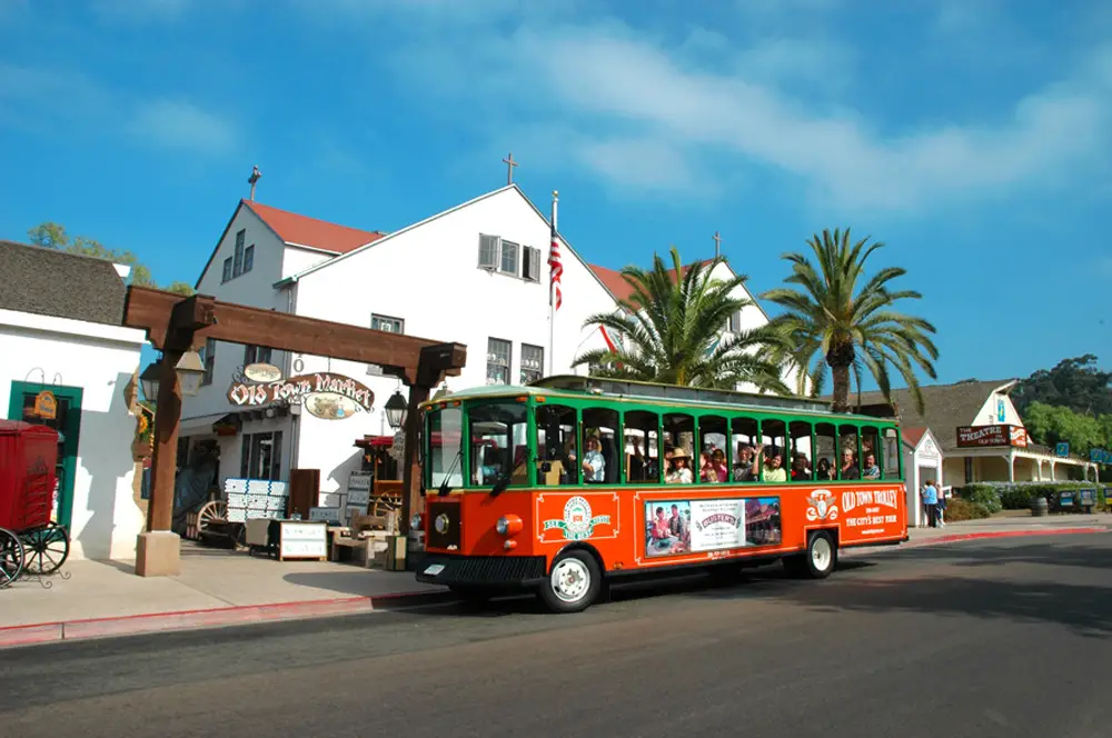 Old Town Trolley Tours of San Diego green and orange bus in front of the Old Town Market.